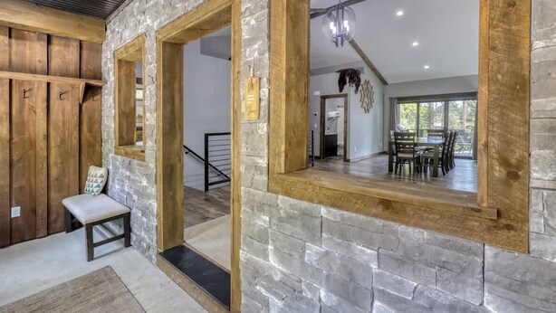 Una habitación espaciosa con pared de piedra, vigas de madera y un ventanal grande.