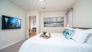 Een hotelkamer met een groot bed, een flatscreen televisie aan de muur en een dienblad met ontbijtartikelen op het bed.