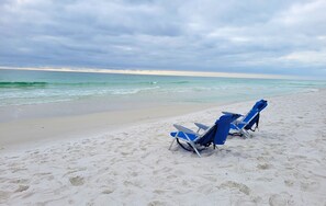 A beach with two blue lounge chairs and a surfboard. - Private Pool + Hot Tub and Golf Cart to Beach (Miramar Beach)