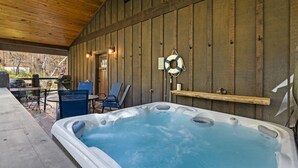 A hot tub area with wooden walls, a lifebuoy, and outdoor seating. - Whiskey Barrel Lodge (Lead)