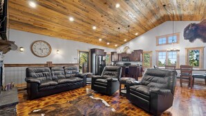 A spacious living room with leather sofas, a large rug, and a wooden ceiling. - Whiskey Barrel Lodge (Lead)