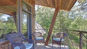 A wooden deck with wicker chairs and a glass door leading to a covered area. - Après Powder Haus – Walk to the slopes!  Hot tub, pet friendly and game garage (Lead)