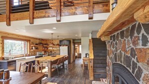 Une cuisine spacieuse avec des plans de travail en bois, une grande table à manger et une cheminée en pierre.
