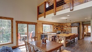 Une cabane en bois spacieuse, dotée d’un grand espace repas, d’une cuisine et d’une chambre à coucher située en mezzanine.