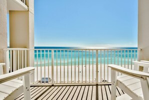 A balcony with white railings and a view of a beach.
