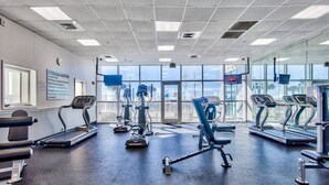 Centro de fitness com esteiras, elípticos e um banco.