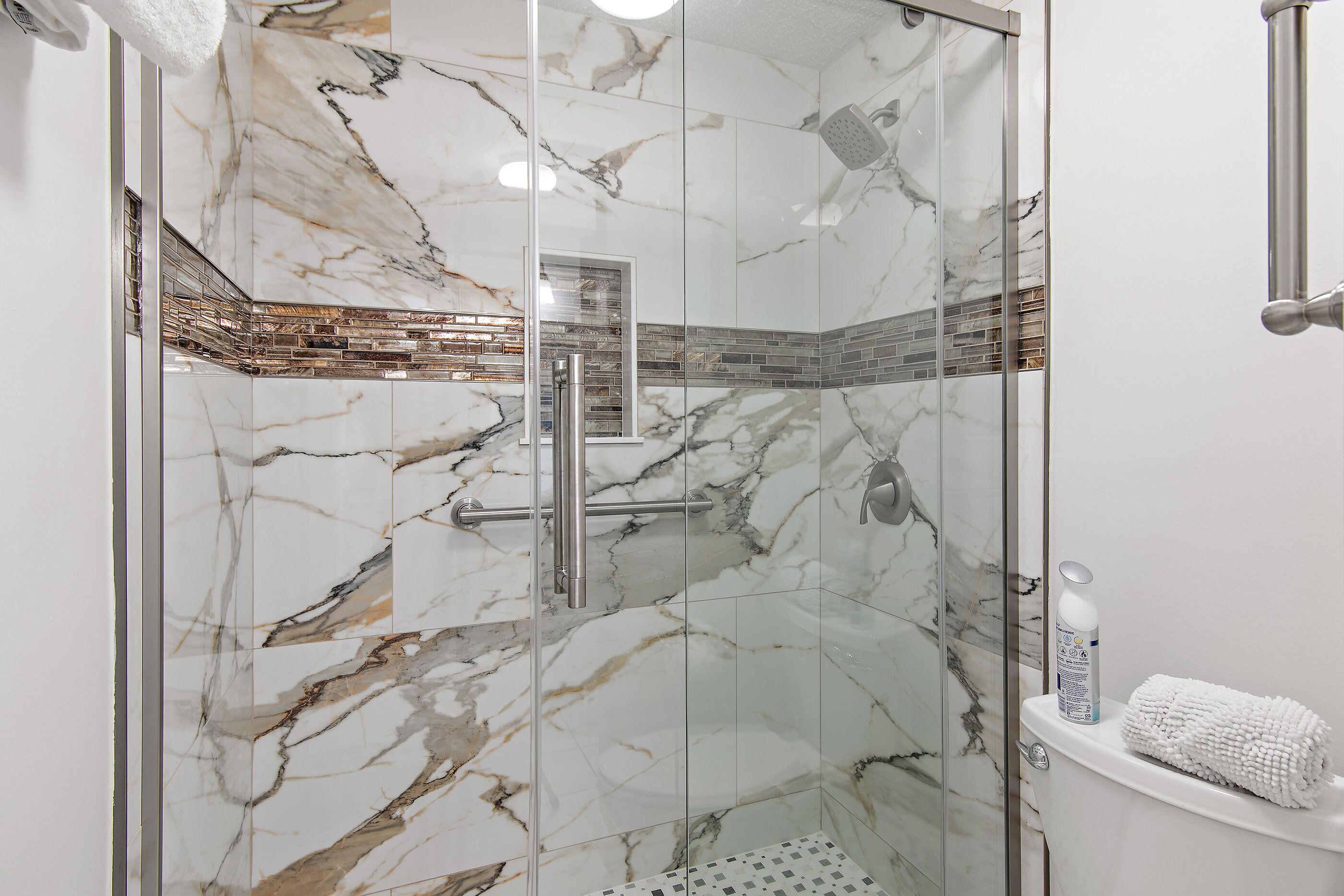 Une douche entièrementClose avec des murs en marbre et un sol carrelé.