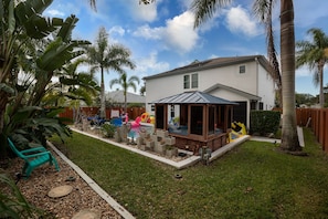 A backyard with a pool, a wooden deck, and a house.