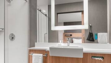 Un baño moderno con un espejo grande, un lavabo y una ducha.