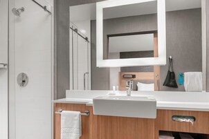 Un baño moderno con un espejo grande, un lavabo y una ducha.