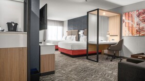 A hotel room with a bed, a desk, a chair, a mirror, and a large abstract painting on the wall. - SpringHill Suites by Marriott Raleigh Apex (Apex)