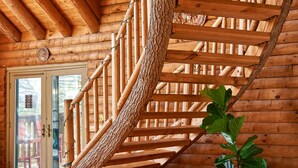 Una escalera espiral de madera en el interior de una cabaña de troncos.