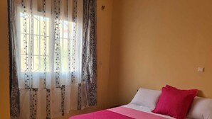 Un dormitorio con cama, cortinas y piso de baldosas.