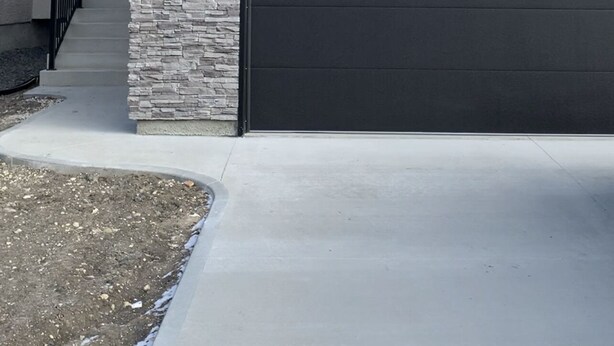 Een modern herenhuis met garage, een gevel van natuursteen en een heldere lucht.
