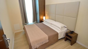 A hotel room with a large bed, a bedside table with a lamp, a wardrobe, and a window with curtains. - San Giuliano (Mestre)