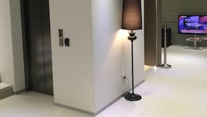 A modern elevator, a standing floor lamp, and a television screen in a hallway. - San Giuliano (Mestre)