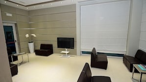 A modern waiting area with sofas, a TV, and a large window. - San Giuliano (Mestre)