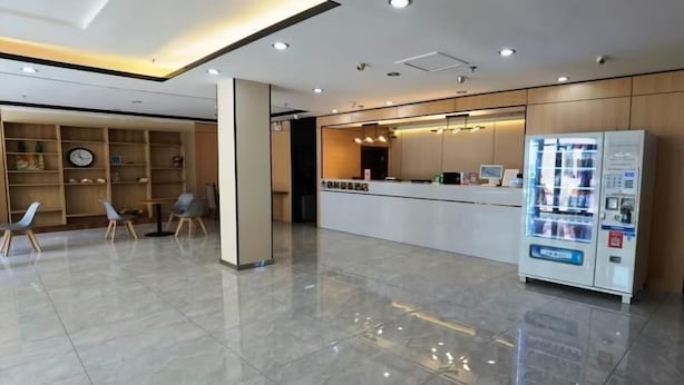 A modern reception area with a reception desk, seating area, and a vending machine. - Greentree Inn Jinan Tianqiao District Railway Station Square Express Hotel (Jinan)