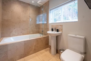 Une salle de bain moderne avec une douche à parois de verre, un lavabo sur colonne et des toilettes.
