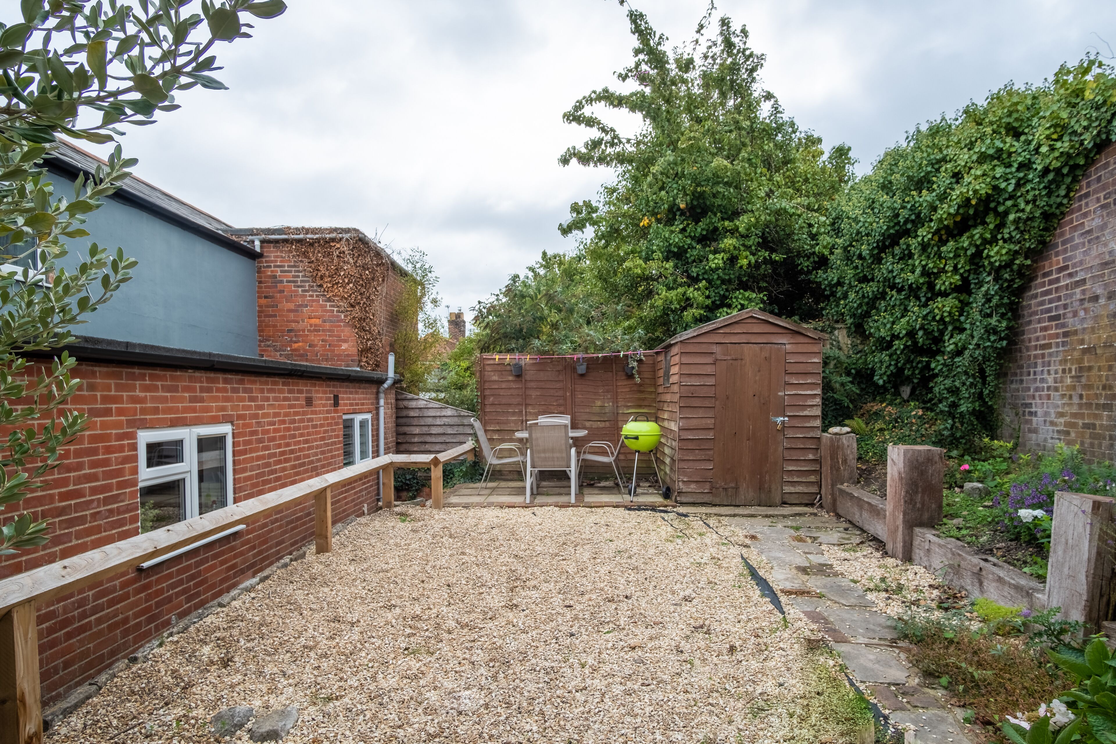 A backyard with a gravel path, wooden fence, and a shed.
