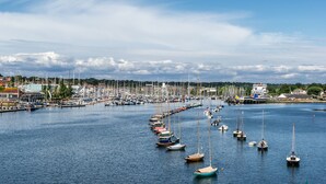 A marina with numerous boats docked, surrounded by buildings and trees. - Sailmaker's Cottage (Lymington)