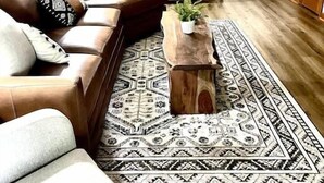 Una sala de estar con un sofá de cuero marrón, una mesa de centro de madera y un tapete estampado.
