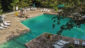Un área de piscina con sillones de descanso y un tobogán pequeño.