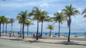 A beach with palm trees, umbrellas, and people. - FLBR 1 BR Condo 1501 - 2 blocks off beach with great Ocean Front Balcony Views. (Fort Lauderdale)