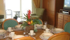 A dining area with a table set for four, surrounded by wicker chairs. There is a cabinet with drawers and a television on a stand. - FLBR 1 BR Condo 1501 - 2 blocks off beach with great Ocean Front Balcony Views. (Fort Lauderdale)