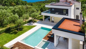 A modern two-story house with a swimming pool, surrounded by lush greenery and a view of the sea. - Luxury Villa Perfecta with Pool (Labin)