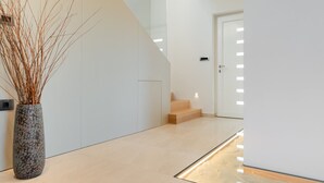 A modern interior with a staircase, a door, and a vase with branches. - Luxury Villa Perfecta with Pool (Labin)