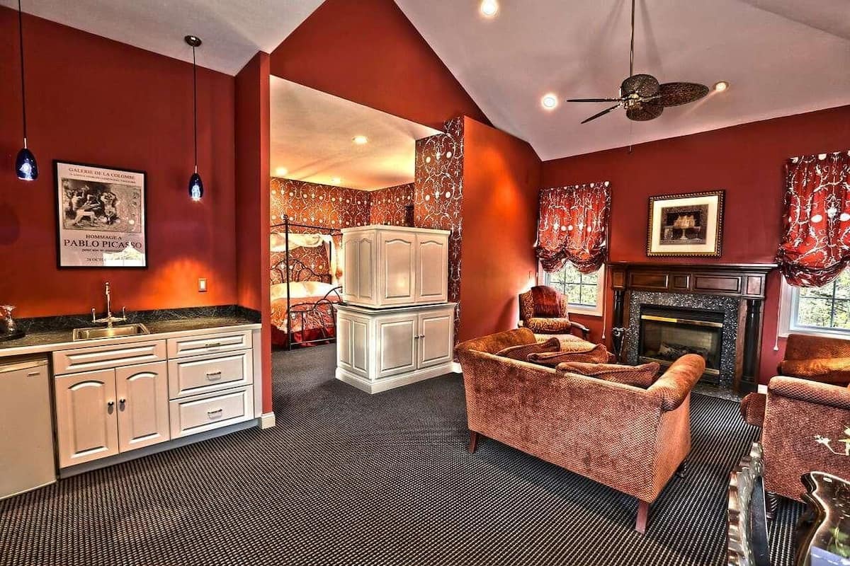 A room with a fireplace, a sofa, a cabinet, and a ceiling fan.