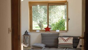 Un salón acogedor con sofá, almohadones, un adorno de estrella y una ventana con vistas al verdor.