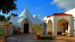 Un edificio tradicional con fachada de piedra, una estructura en forma de cúpula blanca y un tejado de tejas rojas.