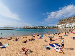 A crowded beach with people sunbathing and swimming. - 20 meters from the beach, private parking and AC (Mogán)