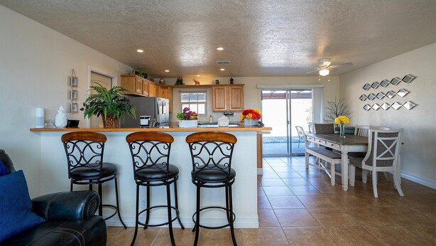 A spacious kitchen with a central island, bar stools, and a dining area with a table and chairs. - Mescal Loop Hava-Gataway (Lake Havasu City)