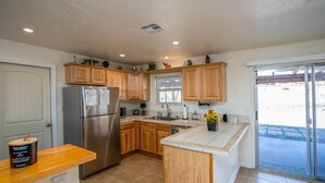 A modern kitchen with wooden cabinets, a stainless steel refrigerator, a built-in oven, and a large island with a sink. - Mescal Loop Hava-Gataway (Lake Havasu City)