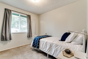 Ein Schlafzimmer mit einem Einzelbett, einem Nachttisch und einem Fenster mit Vorhängen.