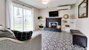 Ein Wohnzimmer mit Kamin, Deckenventilator und einem darüber angebrachten Fernseher.