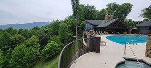 A pool area with a view of mountains, surrounded by lush greenery.