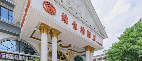 A hotel entrance with a prominent sign, columns, and a clear sky.