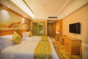 A hotel room with two beds, a television, a wooden cabinet, and a bathroom visible through an open door.