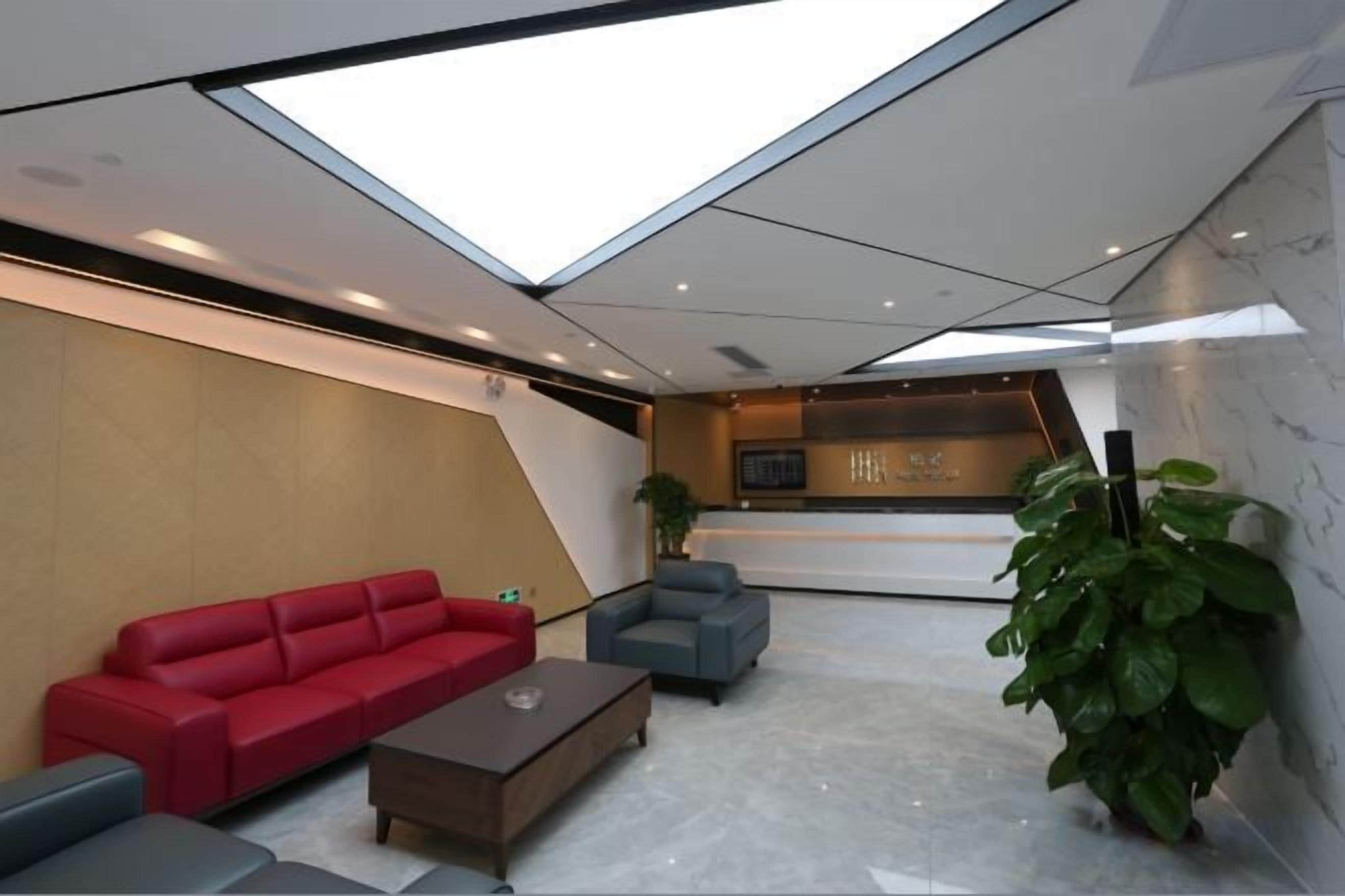 A modern interior with a reception desk, seating area, and a skylight.
