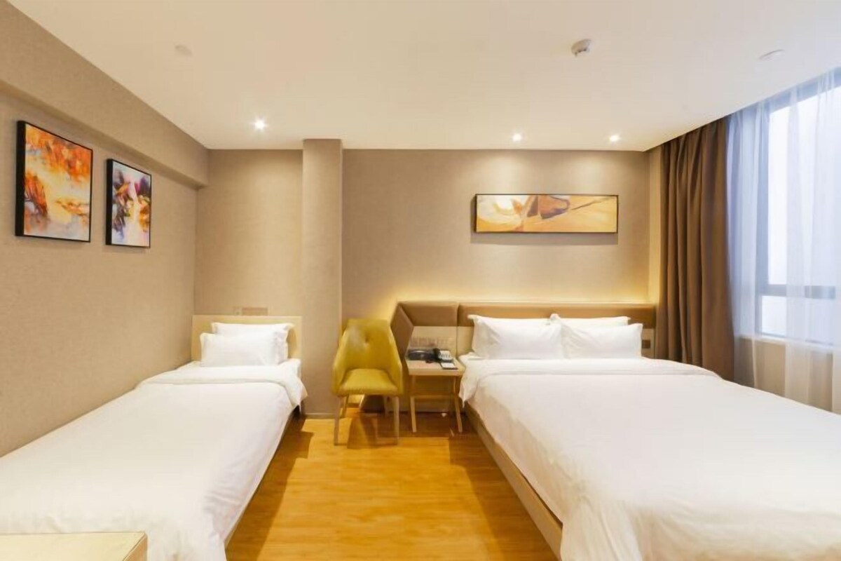 A hotel room with two beds, a desk, a chair, and artwork on the walls.