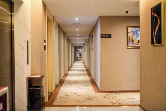 A hotel hallway with a marble floor, framed artwork, and a sign indicating the direction to the lobby.