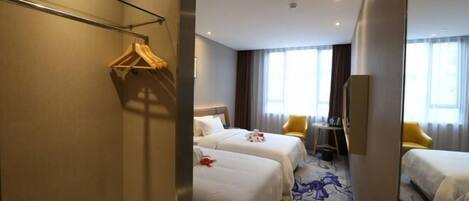 A hotel room with two beds, a mirror, a wardrobe, a desk, and a chair.