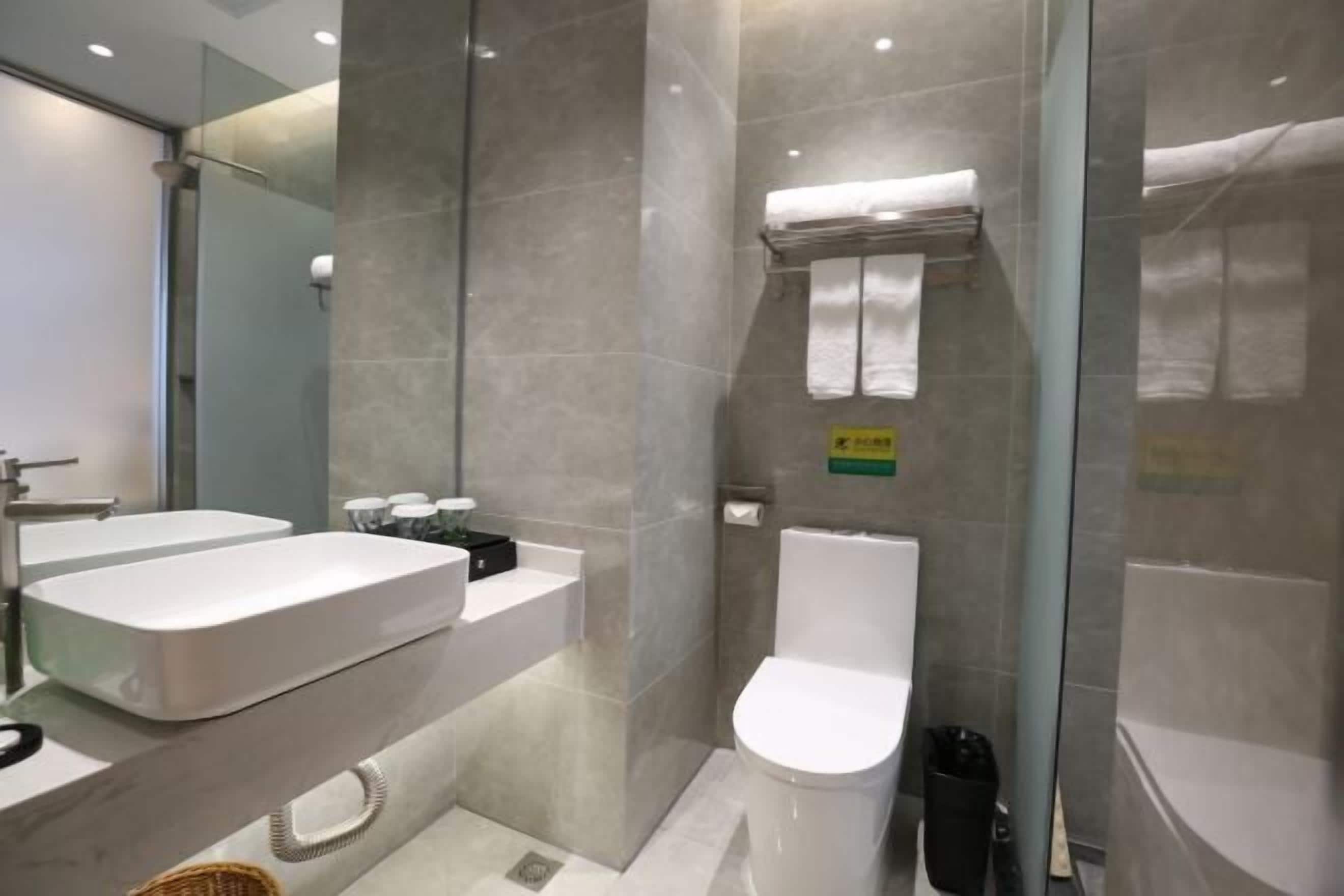 A modern bathroom with a large sink, toilet, and glass shower enclosure.