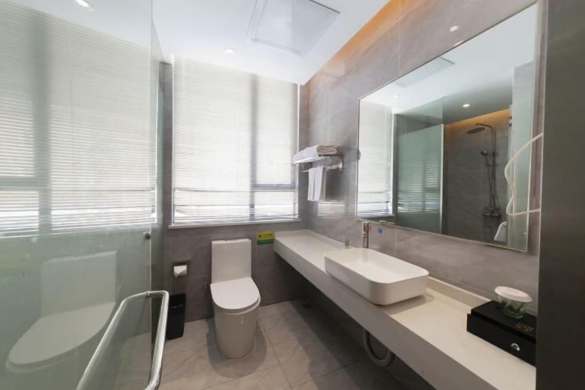 A modern bathroom with a glass shower enclosure, a toilet, a sink, and a large mirror.