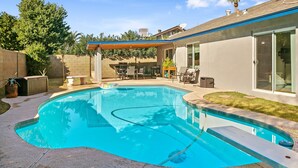 Un patio trasero con piscina, mobiliario de jardín y una zona de estar techada.