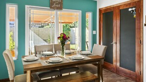 Un comedor con una mesa dispuesta para cuatro, un florero con flores y un letrero sobre la puerta que dice "Bless Our Nest".